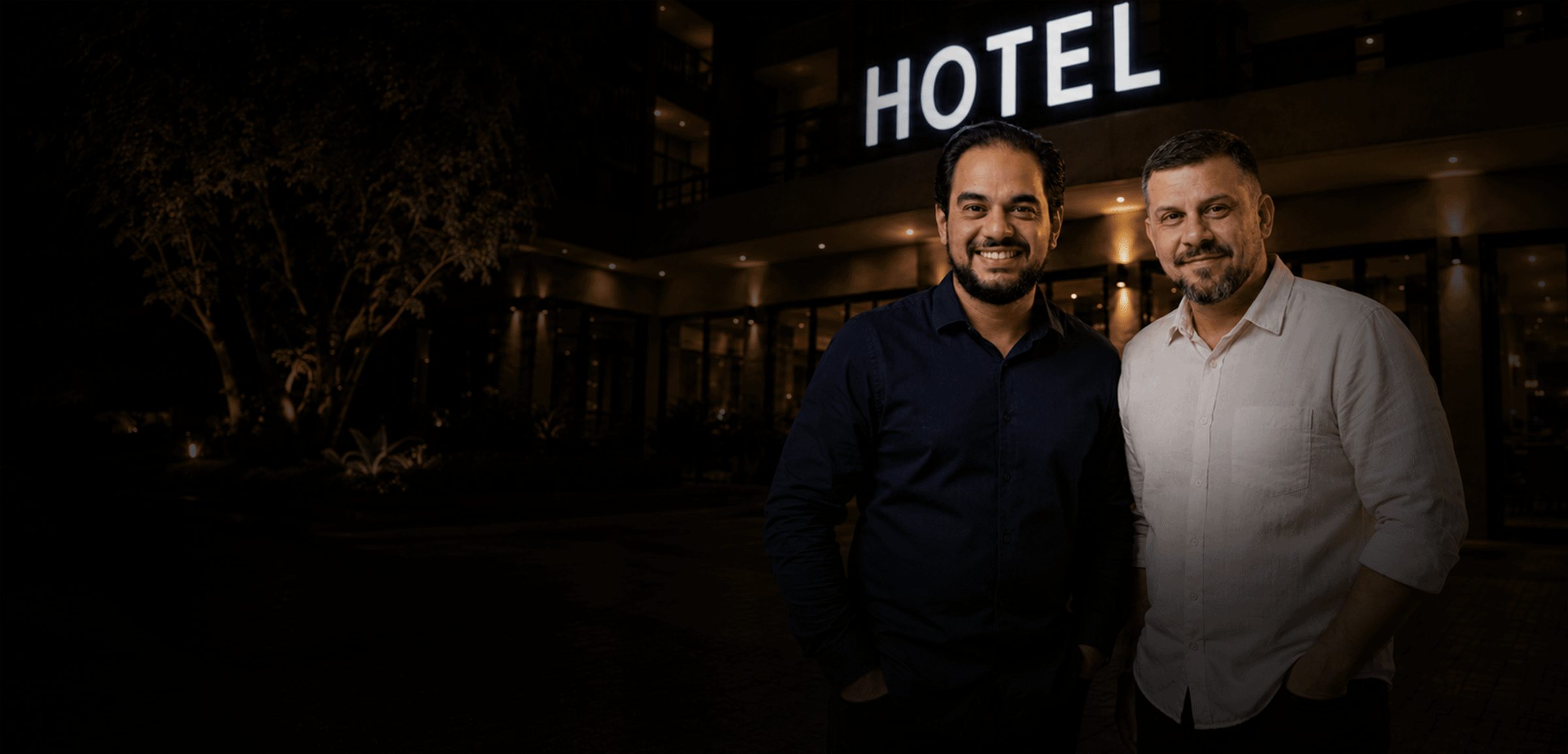 Pérsio Vieira e Renan Gonçalves em frente a um hotel